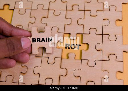 A hand adds a puzzle piece labeled 'brain' to reveal 'rot,' symbolizing thought process. Stock Photo