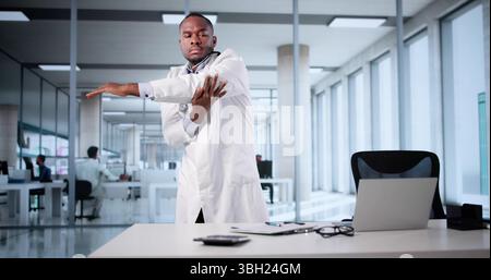 African American Doctor Stretching In Office After Long Day's Work. Stock Photo