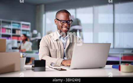 African Fashion Designer Using Laptop In Sunny Design Studio Office. Stock Photo