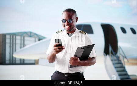 Professional African American Pilot In Uniform Smiling At Airport Departure. Stock Photo