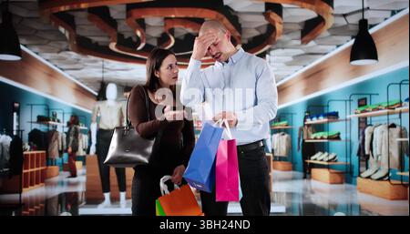 Confused Customer At Mall With Receipt Faces Cost Inflation Shock. Young Woman Checking Phone, Upset By Price Increase Stock Photo