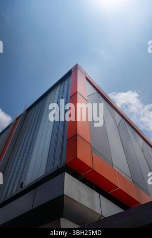 The building has a red trim and is tall. The sky is blue and there are clouds in the background Stock Photo