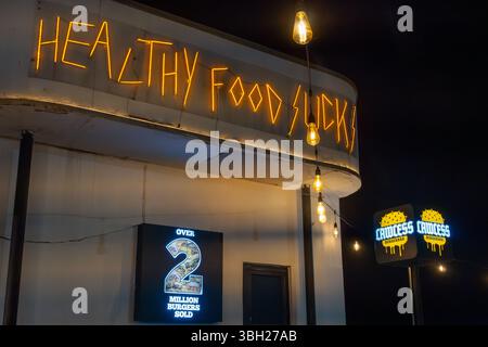 Jakarta, Indonesia - February 9, 2025: Restaurant with a neon sign that says Lawless. There are tables and chairs outside and inside Stock Photo