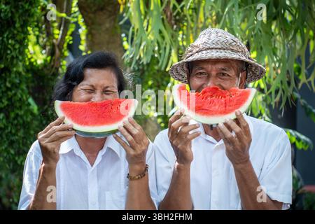 Elderly couple sharing a joyful moment with watermelon, showing love, laughter, and the warmth of lifelong companionship Stock Photo