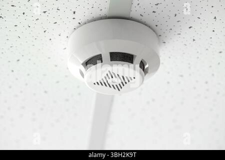 Modern smoke detector on ceiling in room, closeup Stock Photo