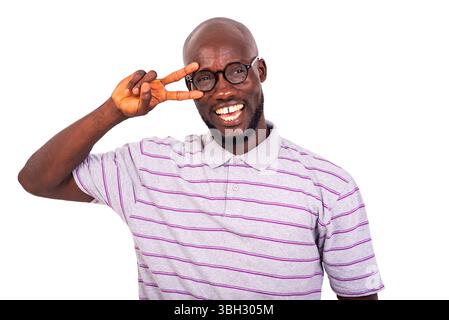 young happy man wearing optical glasses showing victory gesture with two fingers over eyes while smiling. Stock Photo