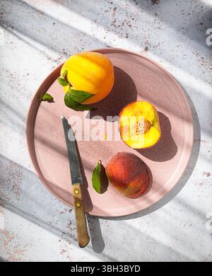 Vibrant peaches and nectarine on a pink plate with a vintage knife. Stock Photo