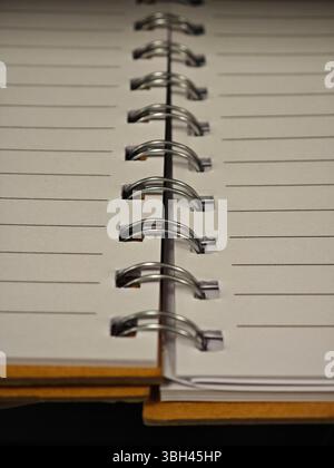 A spiral notebook with blank pages lies open on a wooden surface, inviting ideas for creative writing or study notes. The simple design encourages org Stock Photo