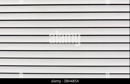 Wide view of several rows of tan vinyl siding in very good condition in morning light. Stock Photo