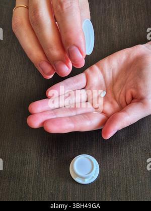 hand holds pills. in hands a jar with pills, drugs. small white pill in hand Stock Photo