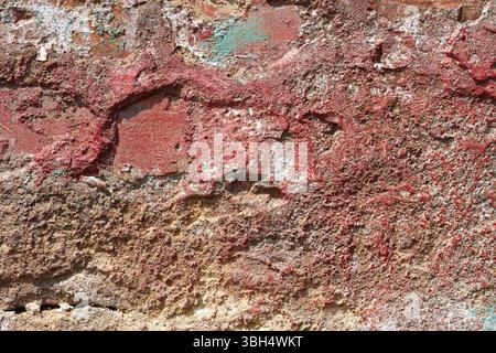 Part of ancient brick wall with plaster partly shelled and partially painted in red Stock Photo