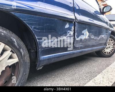 Blue car, dent in a door in the street after a broken accident. Scratched car body. Dented Stock Photo