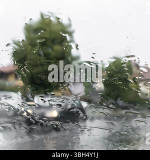 Blurred view of road through wet car window. Rainy weather. Safety Stock Photo