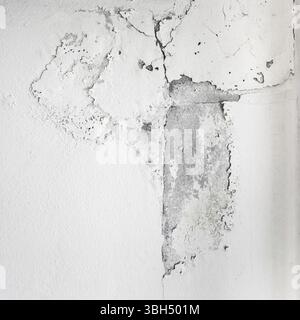 White cracked paint on wall. Peeling painted wall, texture, grunge background, cracked paint with white wall with window Stock Photo