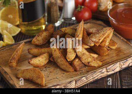 Rustic spicy fried potato slice on a wooden plate, with tomato sauce and beer Stock Photo
