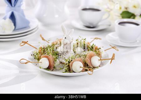 Appetizer quail egg stuffed with alfalfa sprouts with a slice of salmon, on a wooden skewer. Buffet serving for the Easter table Stock Photo