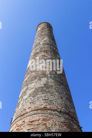 Bottom view of the old brick chimney isolated on a blue sky background Stock Photo