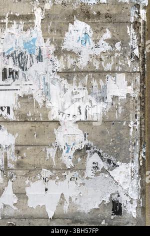 Concrete wall with colorful ripped bill posters. Grunge background Stock Photo
