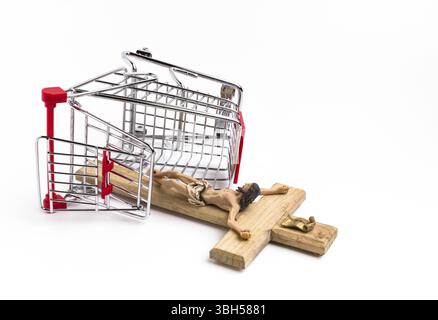 Shopping cart overturned with crucifix on the ground. Conceptual representation of commodification of religion, loss of faith, blasphemy Stock Photo