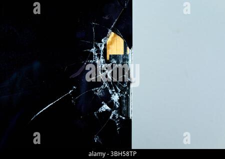 Window is shattered and the glass is scattered on the floor. The broken window is on a wall with a white background. Stock Photo