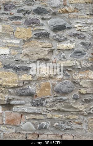 Ancient wall made up of irregular stones with warm colors Stock Photo