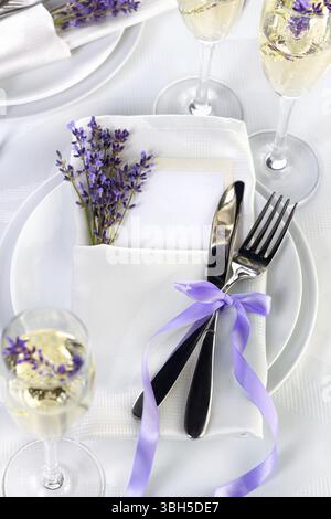 Dining table in Provence style, with Lavender Champagne, folded napkin with cutlery, decorated with fresh lavender. Detail of the wedding dinner. Wedd Stock Photo