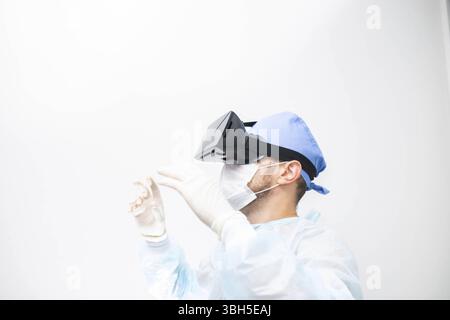 Individual in medical attire using VR headset, exploring technology Stock Photo