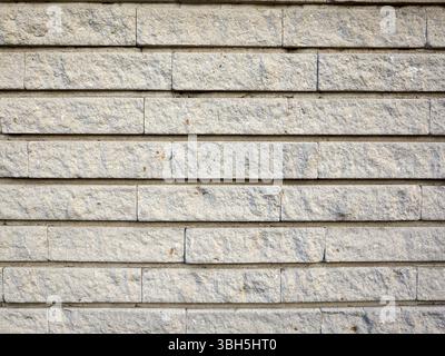 Wall made of white bricks. The bricks are not perfectly aligned. There are some cracks in the wall Stock Photo