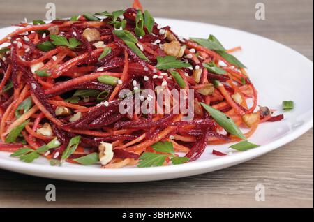 Salad of fresh grated carrots, beets, onions flavored with nuts and sesame seeds Stock Photo