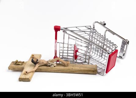 Shopping cart overturned with crucifix on the ground. Conceptual representation of commodification of religion, loss of faith, blasphemy Stock Photo