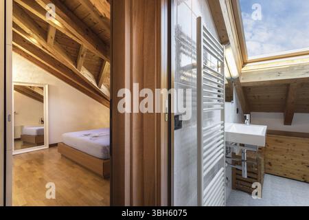 Cozy Interior design in modern bedroom with hallway bathroom of italian apartament with wooden ceiling and exposed beam Stock Photo