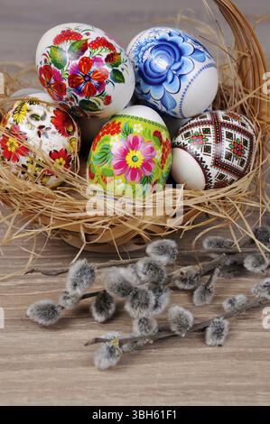 A variety of painted Easter eggs in a basket with willow branches Stock Photo
