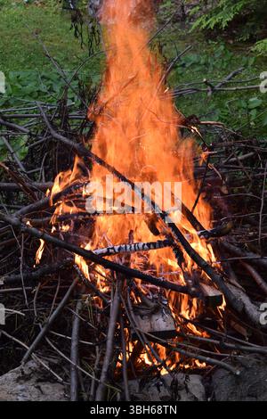 A roaring campfire with tall, dancing flames and crackling logs glowing brightly in the fire pit. Stock Photo