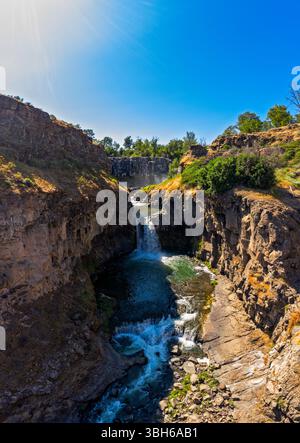 an Aerial view of water with multiple waterfalls next to mountains and ...
