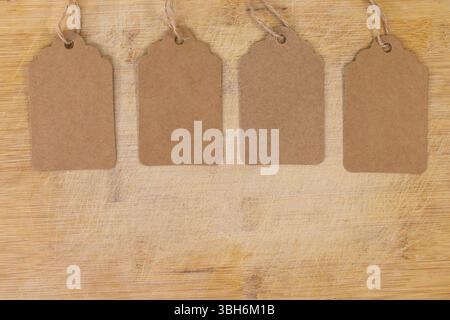 Four Blank Kraft Tags with Twine on Wooden Surface for Product Labeling Stock Photo