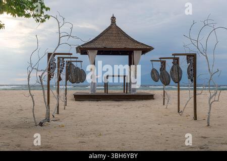 Beach scene with a pavilion and a few hanging lanterns. The pavilion is surrounded by a wooden fence and the lanterns are hanging from the fence. The Stock Photo