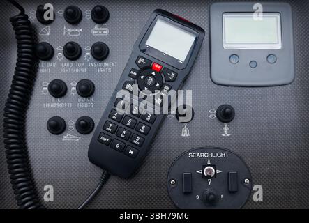 Black dashboard on a motor yacht with control buttons and a radio station, close-up. Walkie-talkie in the control cabin of a motor yacht. Radio statio Stock Photo