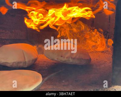 Traditional flatbread baking inside a clay oven Stock Photo
