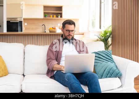 Young business man small startup company owner, working at home, checking the finances on graphs and laptop. Innovative young freelance male calculati Stock Photo