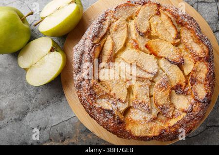 Caramelised apple clafoutis with vanilla and cinnamon close-up on a wooden board on the table. Horizontal top view from above Stock Photo