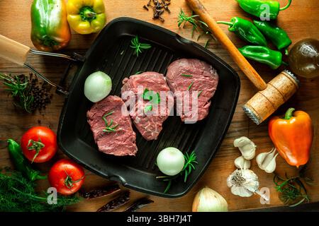 Fresh raw veal steak in pan with vegetables, top view. Stock Photo