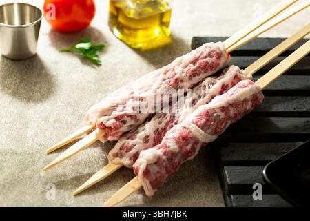 Raw lamb skewers ready for grilling, wrapped in lamb fat. Stock Photo