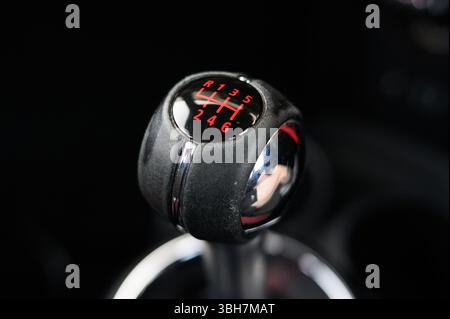 A close up of a gear shift with the numbers 1 through 6 on it. The gear shift is red and black Stock Photo