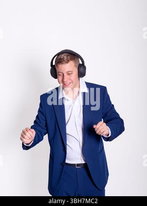 Full body of handsome young businessman listening music and dancing feeling relaxed isolated on white background. Stock Photo
