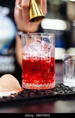 Crafting a vibrant cocktail with precision at a lively bar in the evening Stock Photo