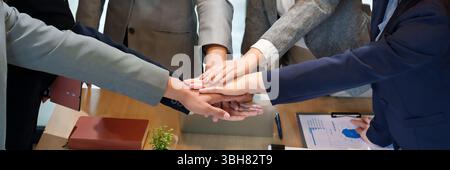 A diverse group of business people put their hands together to illustrate collaboration unity support successful startup project motivated staff for c Stock Photo
