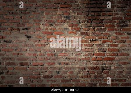 Vintage red brick wall with visible cracks and rough cement. Old industrial texture background with light and shadow. Ideal for construction and archi Stock Photo