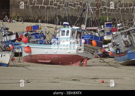 Fishing boats in the harbour on the dry dock, surrounded by a harbour wall and sandy bottom, St Ives, Cornwall, England, Great Britain Stock Photo