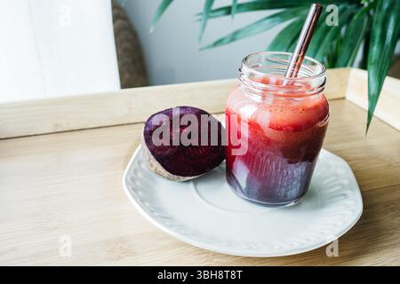 A vibrant beetroot smoothie served in a clear glass, showcasing its deep red color and thick texture. Known for its antioxidant, anti-inflammatory, an Stock Photo
