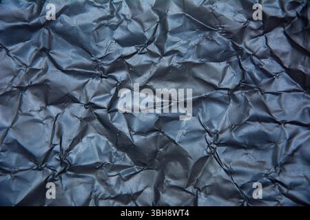 Black background with heavy wrinkles. Recycled black kraft paper texture as background. Stock Photo